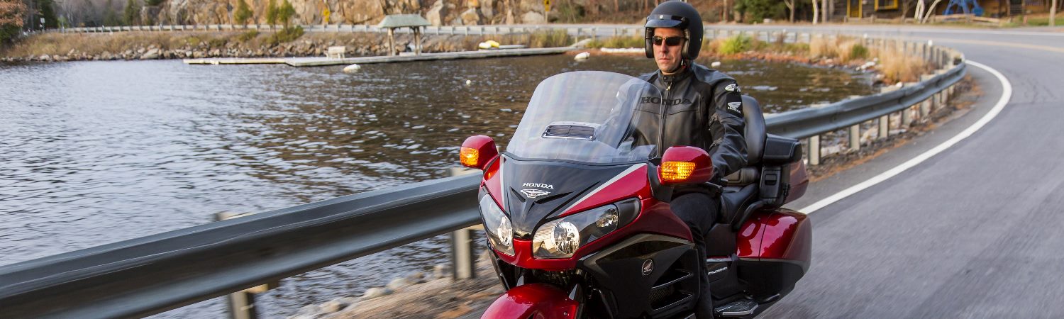 Man riding a 2015 Honda® Gold Wing Action motorcycle past a lake